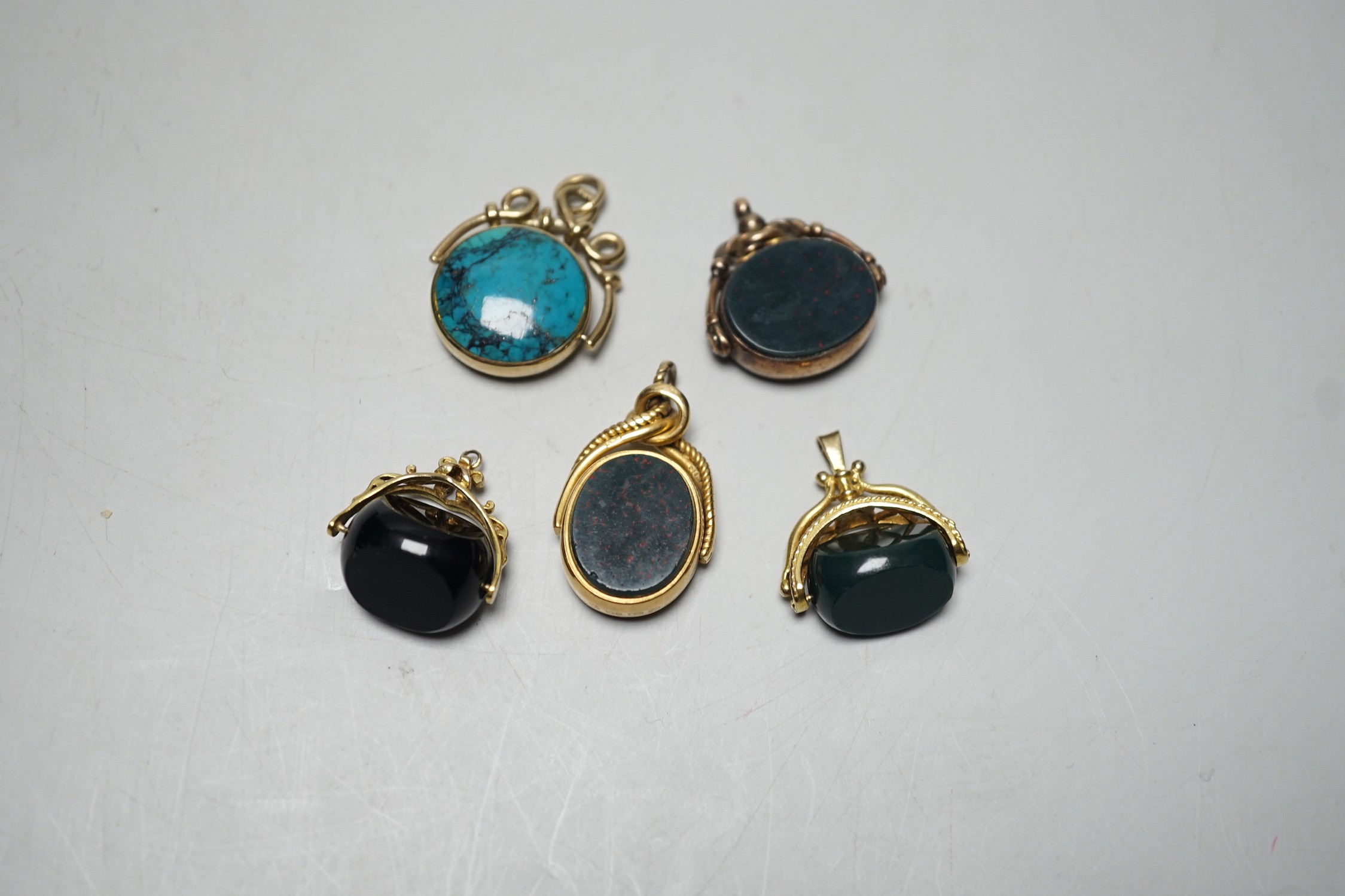 A late Victorian 18ct gold mounted bloodstone and carnelian set spinning fob seal, 36mm, a similar 9ct seal, a yellow metal and turquoise set fob seal and two later 9ct gold mounted seals.